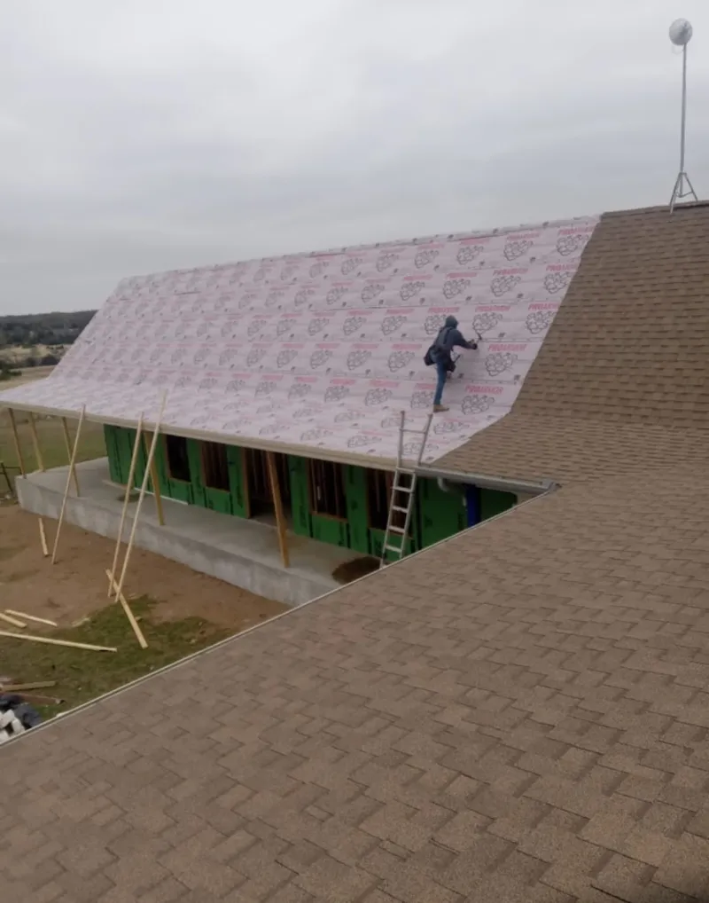 Worker preparing underlayment for a metal roof installation in Bound Brook